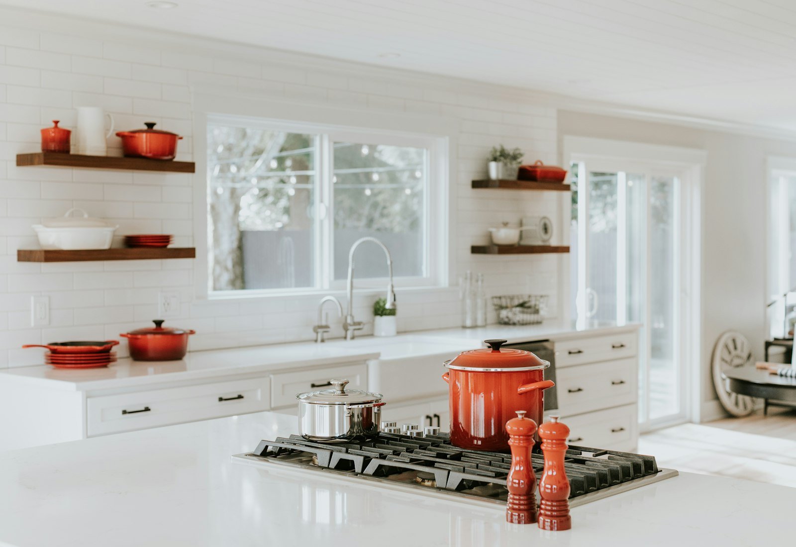 A white shaker kitchen with dark handles and open shelves.