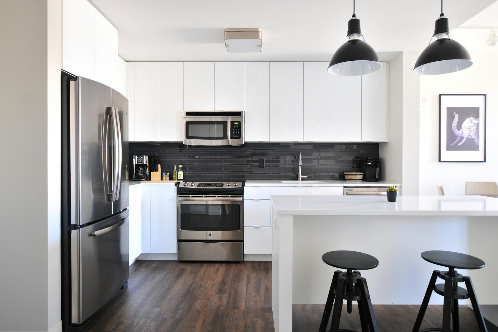 A remodelled white kitchen with tall cabinets and a breakfast island.